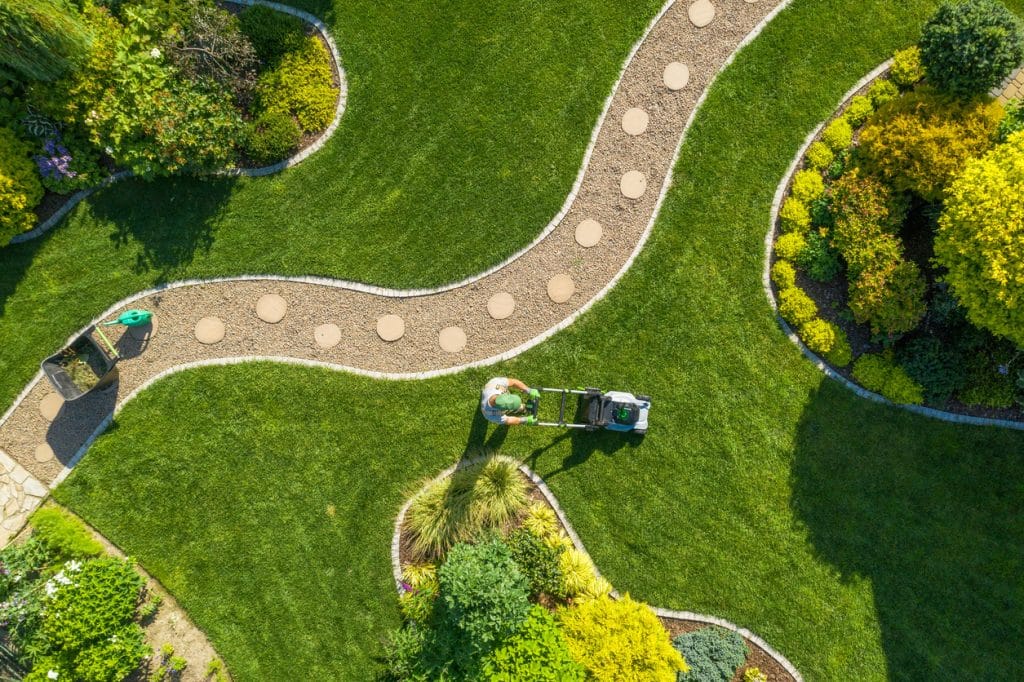 Aerial view of a landscaped garden featuring curved gravel pathways with stepping stones, manicured lawns, and decorative planting beds.