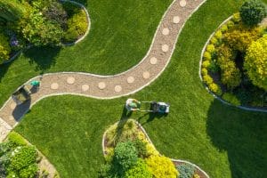 Aerial view of a landscaped garden featuring curved gravel pathways with stepping stones, manicured lawns, and decorative planting beds.